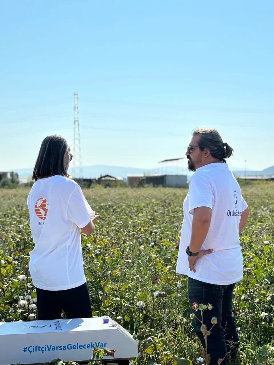 Two Orbiba team members reviewing field conditions beside the robot