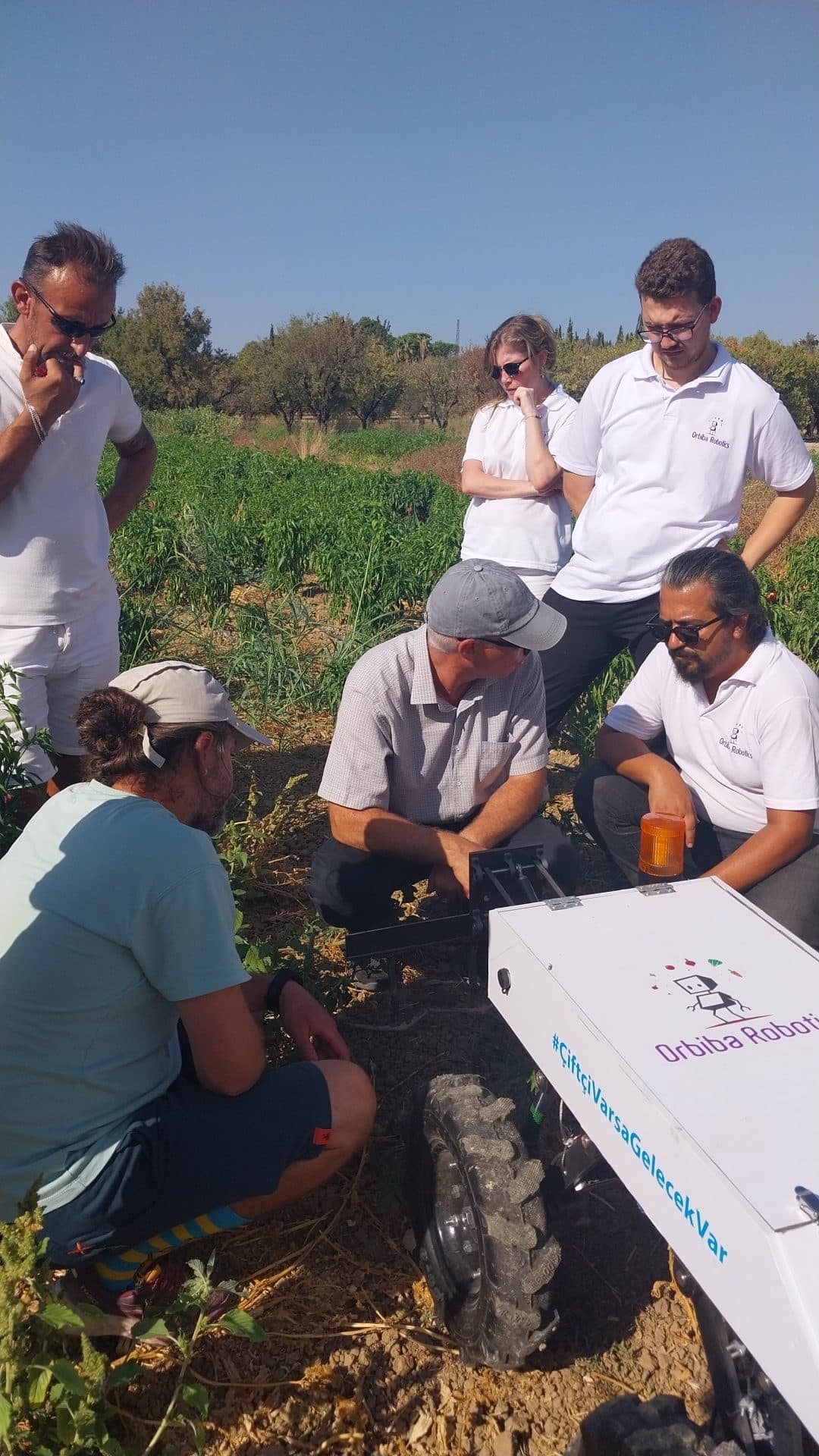 The team gathered around the robot for a field debrief