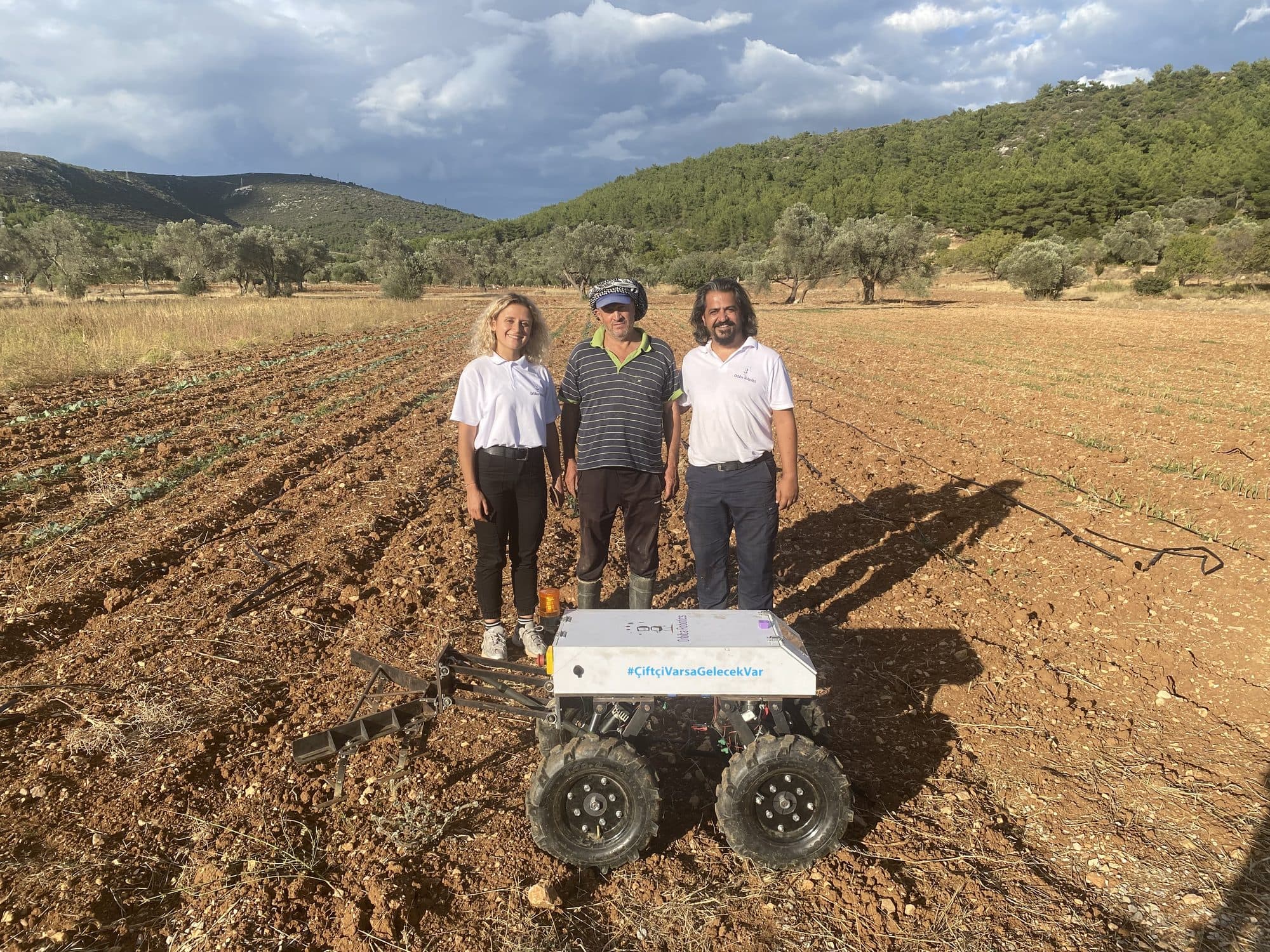 Two Orbiba team members and a farmer standing behind Ecominos in the field