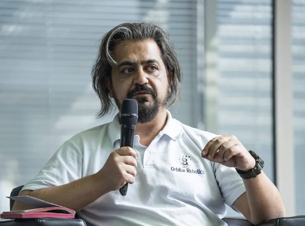 Orbiba Robotics founder and CEO Ilker Bektas speaking with a microphone on a panel